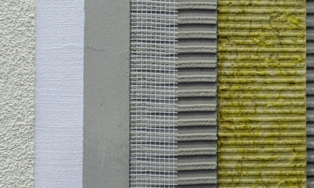 Cross-section of wall insulation layers: plaster, adhesive, reinforcing mesh, adhesive layer, and mineral wool.