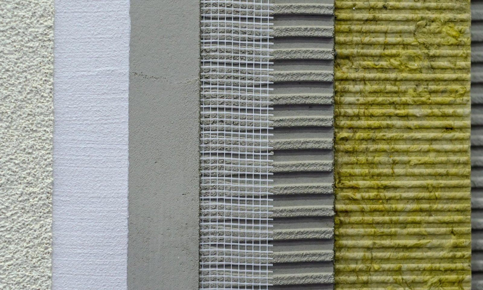 Cross-section of wall insulation layers: plaster, adhesive, reinforcing mesh, adhesive layer, and mineral wool.