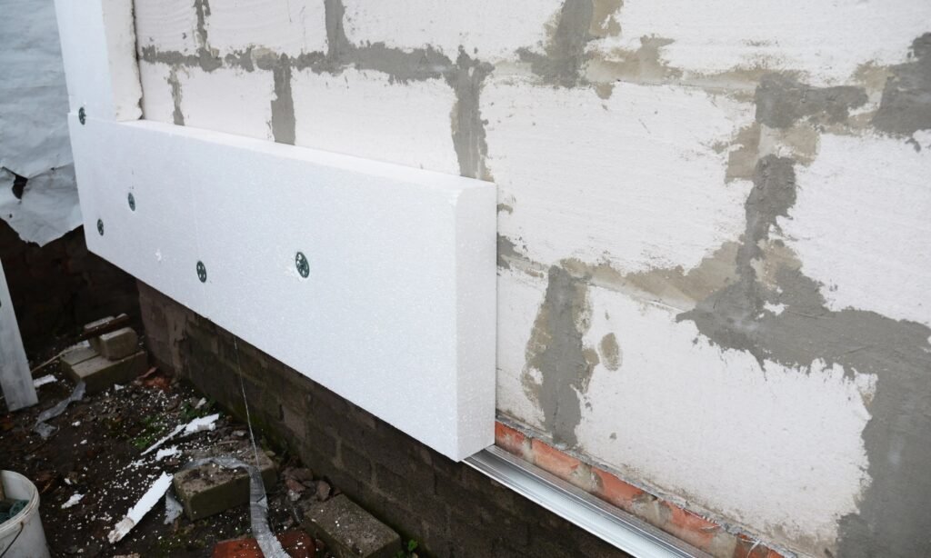 Process of insulating a concrete block wall with polystyrene boards fixed with special dowels.