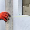 Installation of polystyrene insulation boards using professional adhesive for EWI systems. Proper positioning and leveling of thermal insulation on the building facade.