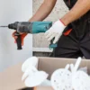 Close-up of a worker using a drill to secure external insulation boards with plastic anchors