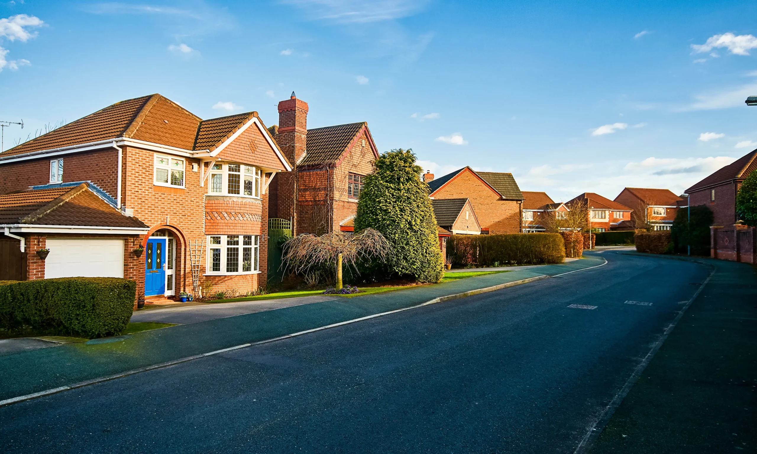 Row of detached brick houses in the UK ideal for external solid wall insulation to improve thermal efficiency and reduce heating costs