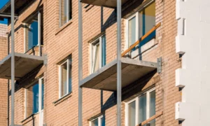 Apartment building facade before external wall insulation, exposed brickwork and concrete balconies visible